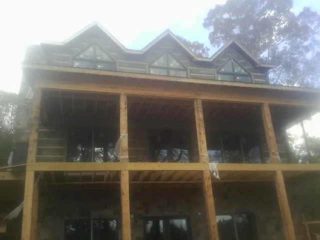 Dormers and porch framing on a large log home under construction — Roof Coating work by our crew in Janesville