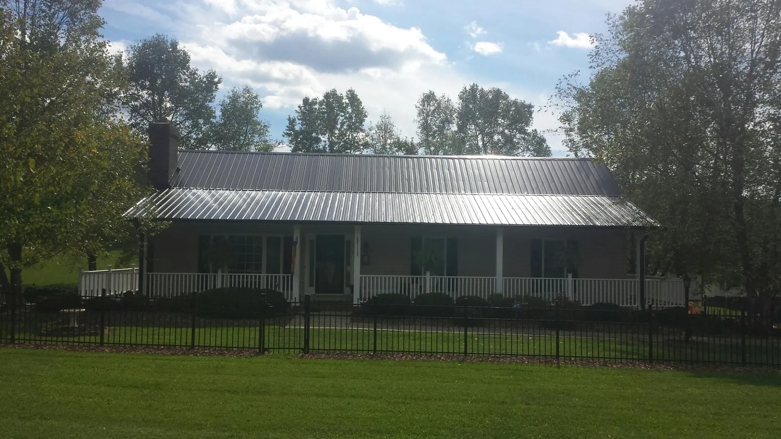 Gray metal roof on a brick ranch with a full width front porch — Gutter Guard Installation work by our crew in Janesville