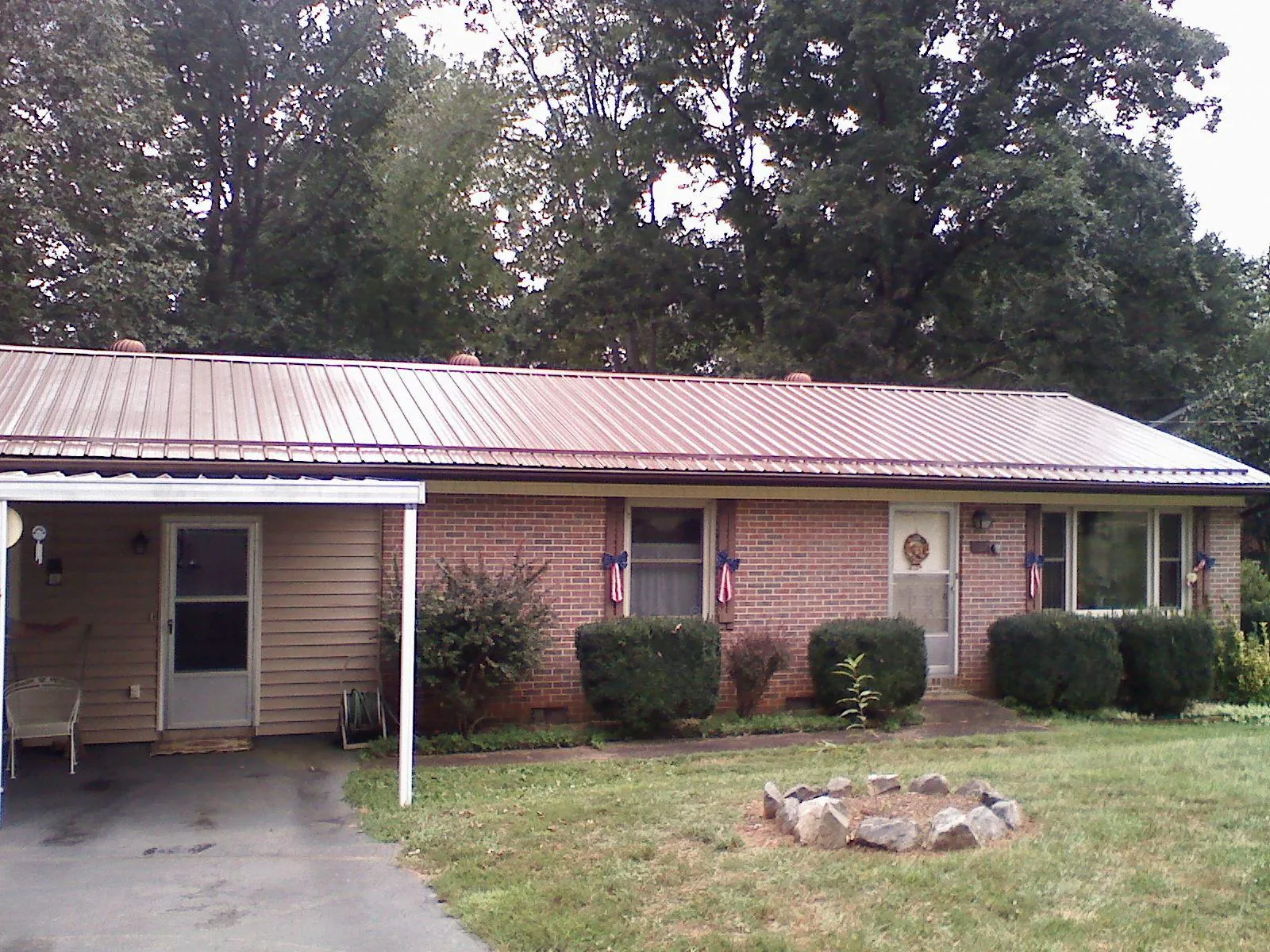 Bronze metal roof and carport on a brick ranch home — Roof Repair work by our crew in Janesville
