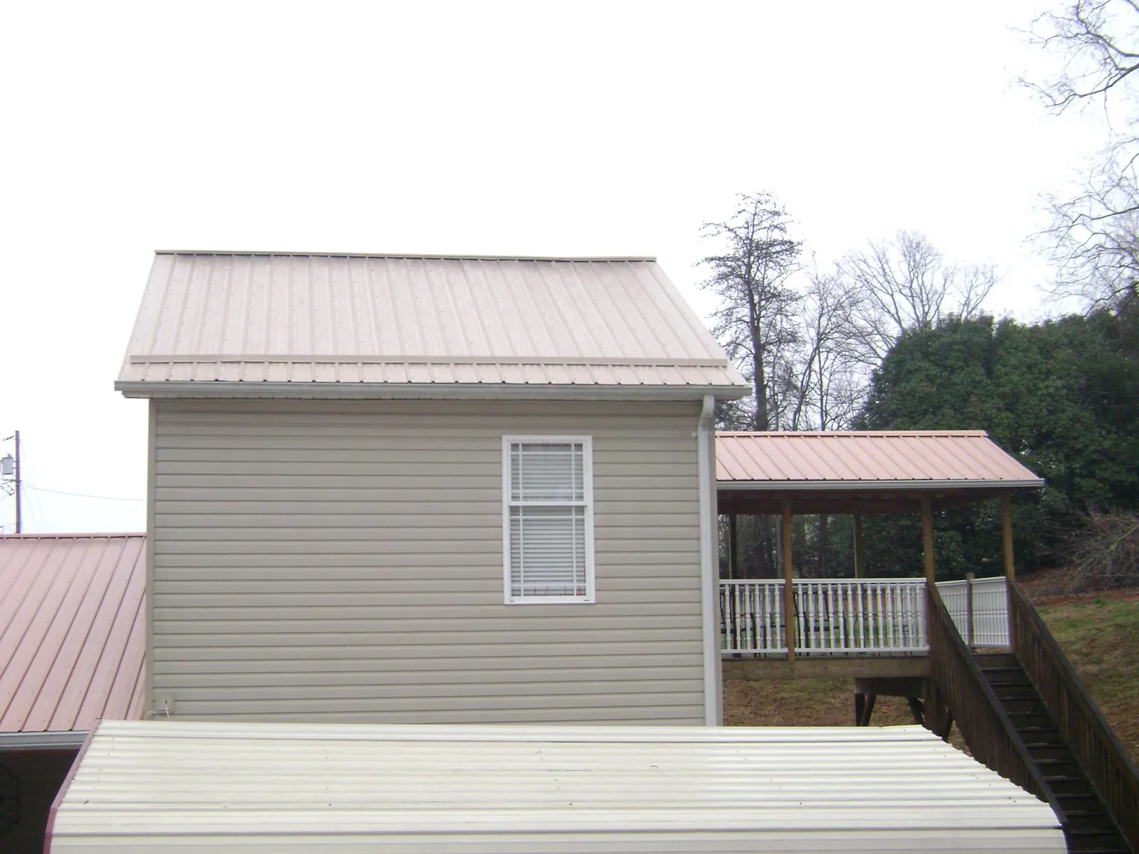Tan metal roofs on a two story addition and attached porch, from a Roof Replacement job in Janesville