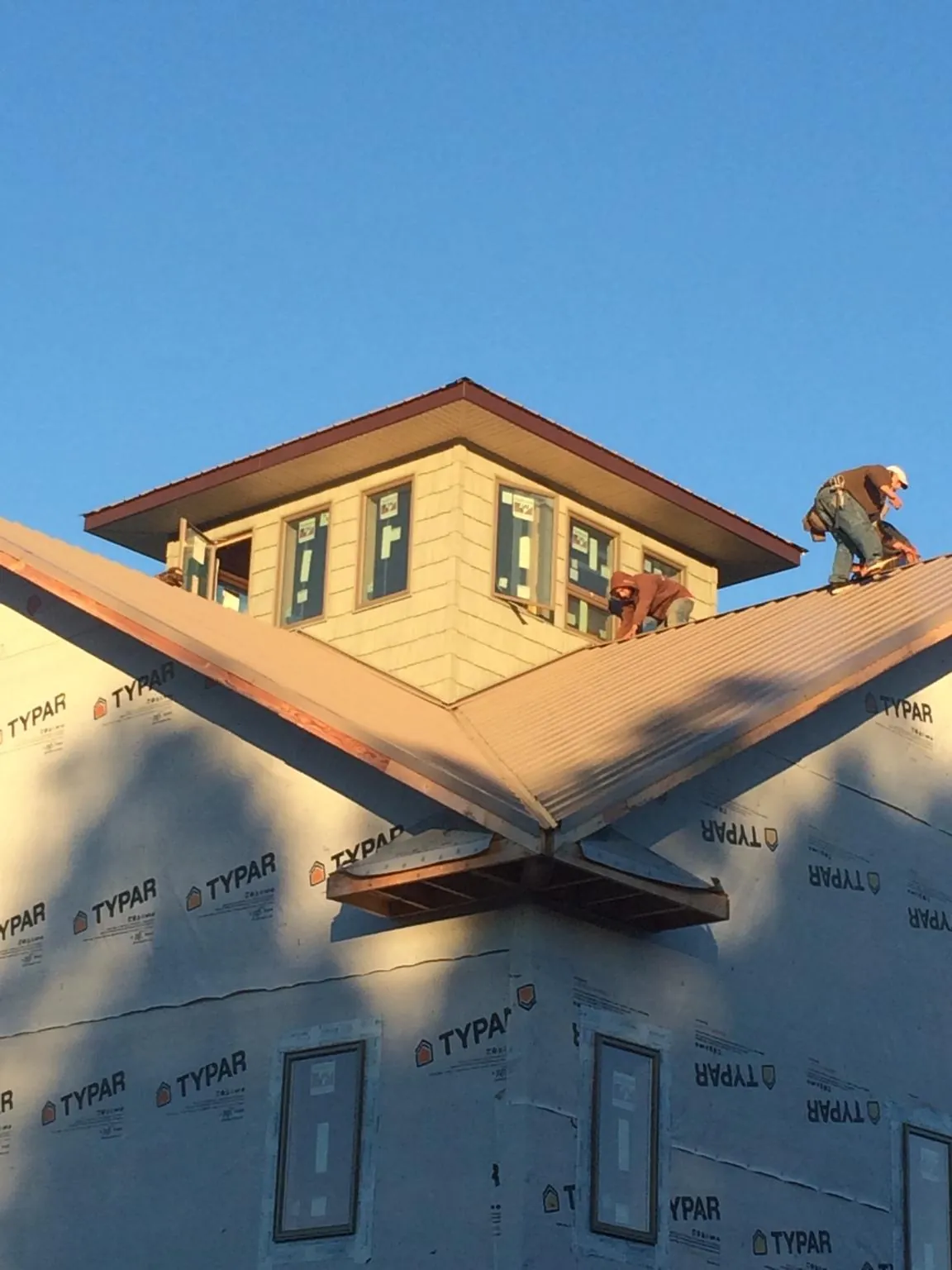 Roofers working around a rooftop cupola on a new metal roof at sunset — Roof Waterproofing in Janesville by Roofing Brothers